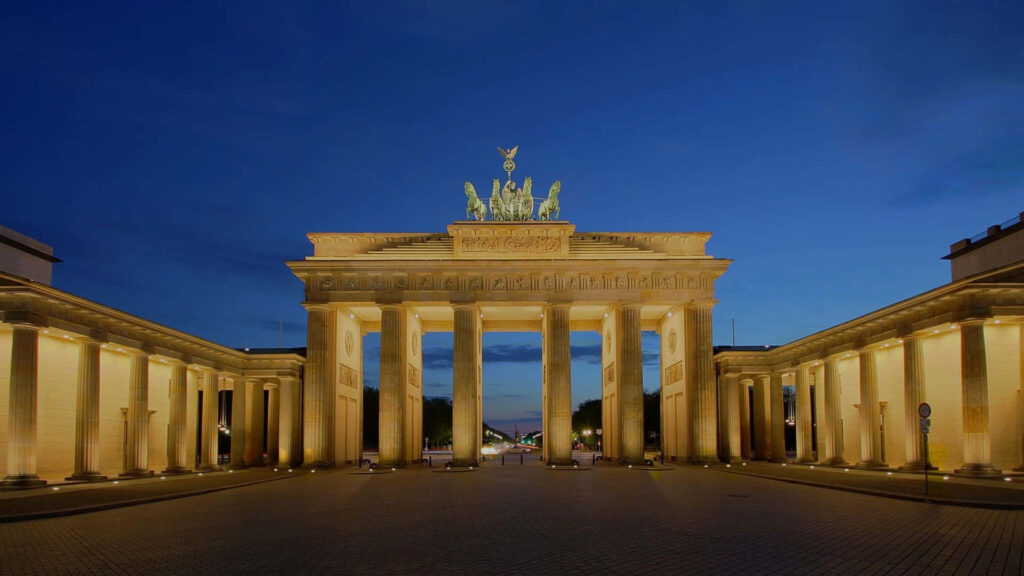 Brandenburg Gate illuminated at dusk with grand columns and iconic quadriga statue Berlin view Wallpaper