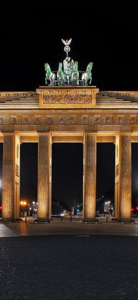Brandenburg Gate illuminated at night with golden lighting and dramatic shadows Berlin landmark wallpaper