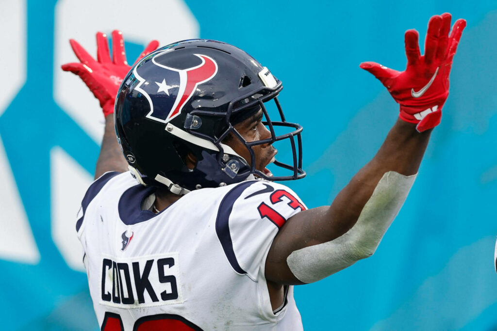 Brandin Cooks Houston Texans NFL wide receiver celebrating with hands up in vibrant teal background Wallpaper