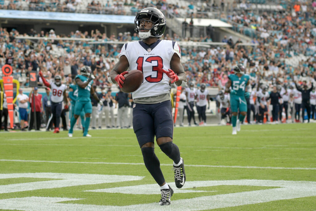Brandin Cooks sprinting on football field in Houston Texans uniform vibrant sports wallpaper background