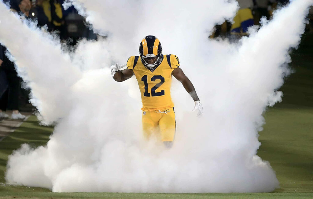 Brandin Cooks in bold yellow Rams uniform emerging through smoke with intense NFL action energy Wallpaper
