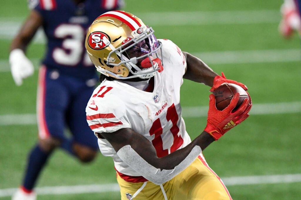 Brandon Aiyuk mid-catch in white gold red San Francisco 49ers uniform NFL game action wallpaper