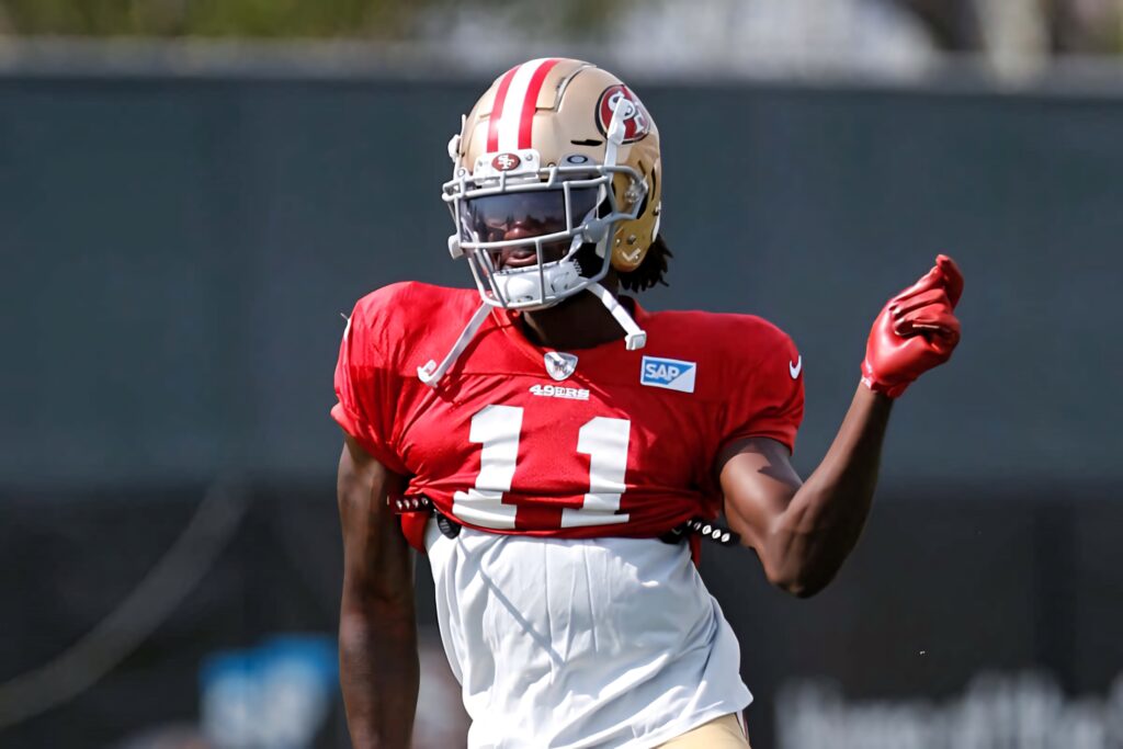 Brandon Aiyuk 49ers practice session action in red gold uniform on NFL football field background Wallpaper