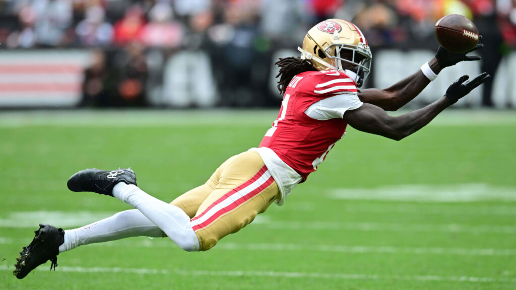 Brandon Aiyuk airborne catch in full stride football action vibrant team colors wallpaper background