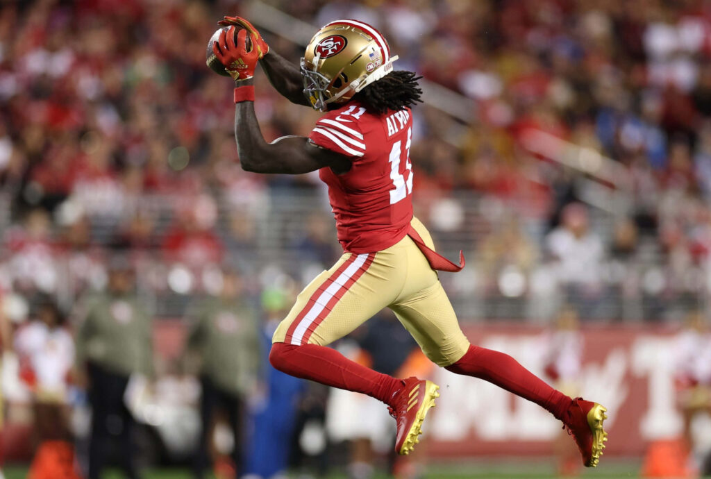 Brandon Aiyuk San Francisco 49ers mid air catch red gold uniform dynamic football action wallpaper