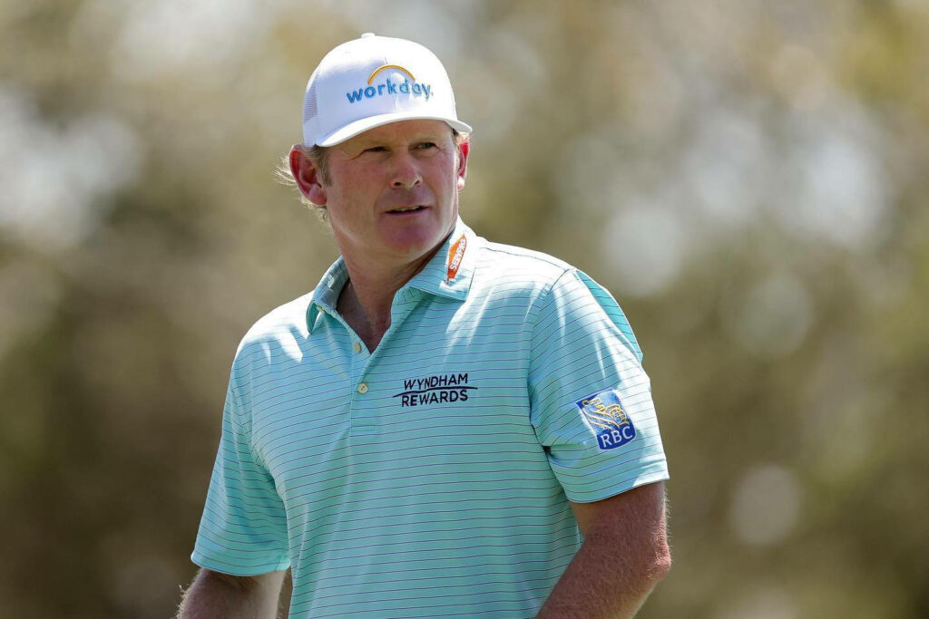 Brandt Snedeker focused on golf course wearing light blue striped polo and white cap in sunlight Wallpaper