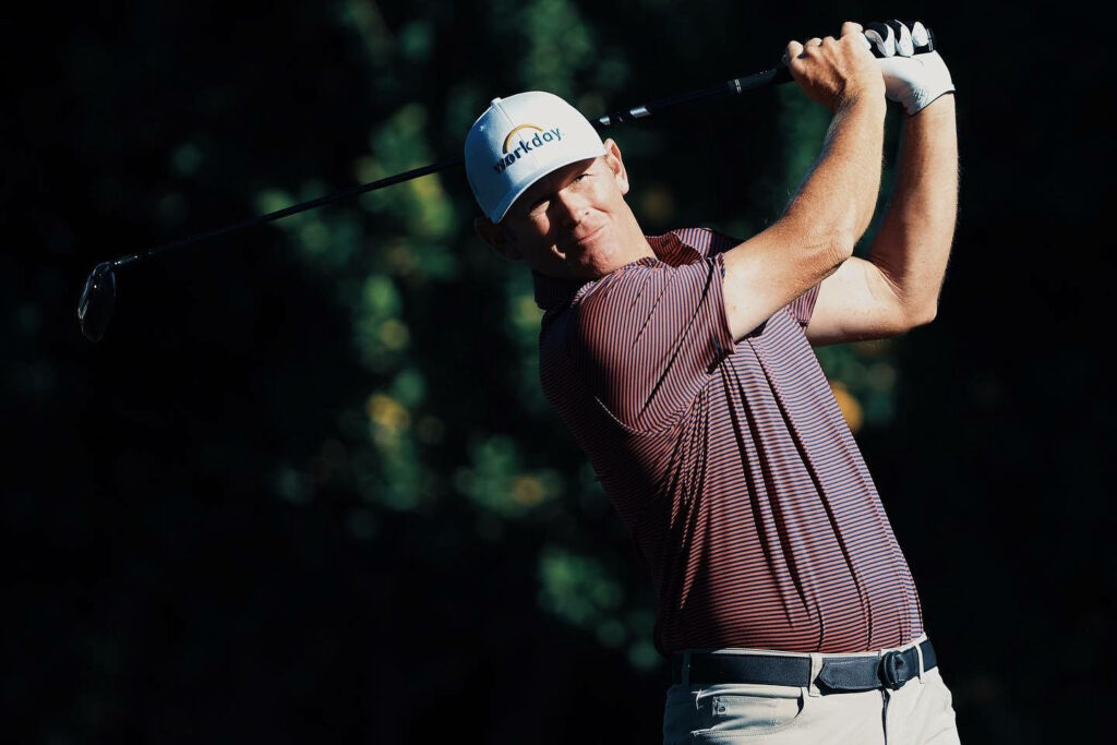 Brandt Snedeker focused golf swing wallpaper with maroon shirt white cap lush green background