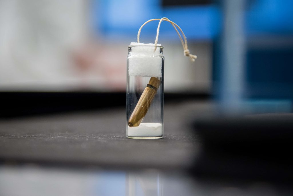 Macro photo of brass rifle cartridge in glass vial with white powder minimalist wallpaper background
