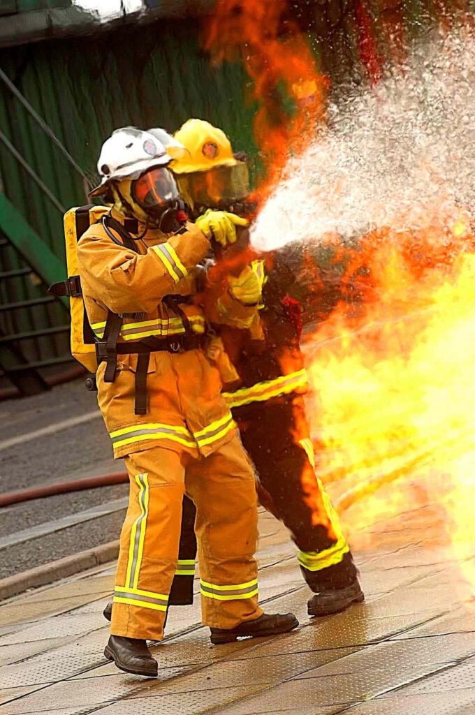 Firefighter in full gear battles intense flames communicating on phone showing bravery and response Wallpaper