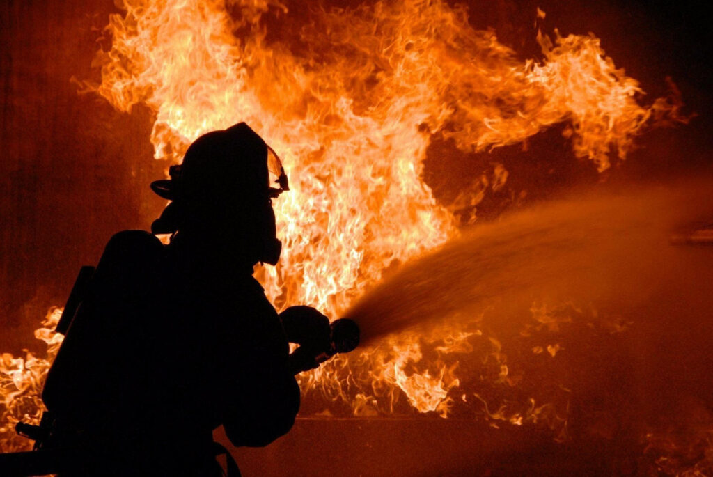 Silhouette of firefighter battling intense flames showing courage and determination wallpaper