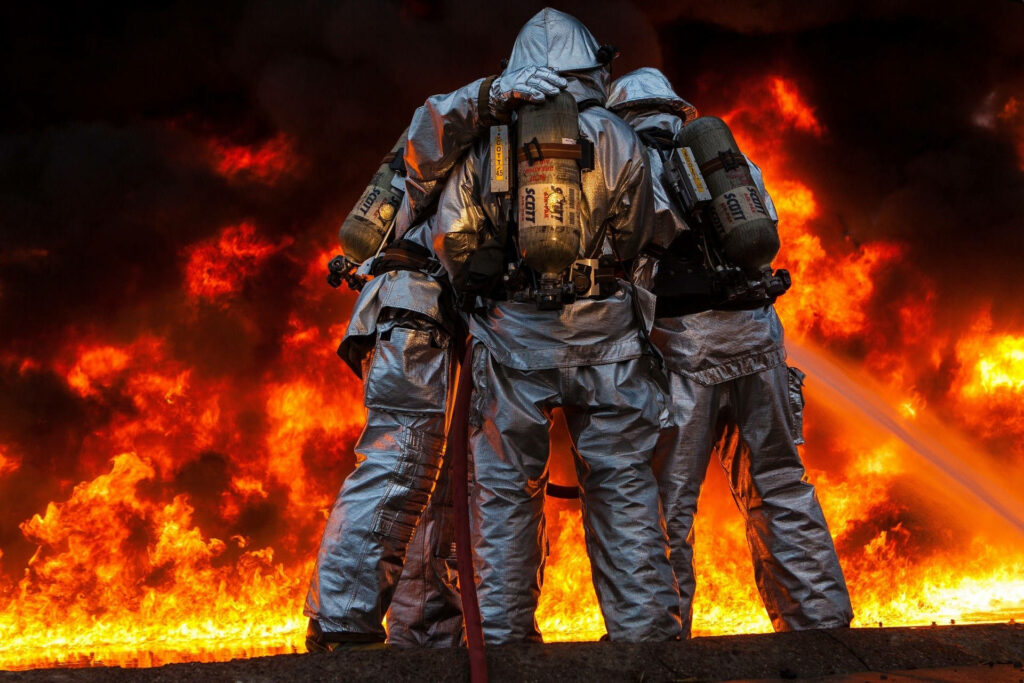 Firefighters in reflective gear fight intense blazing fire united in dramatic wallpaper background