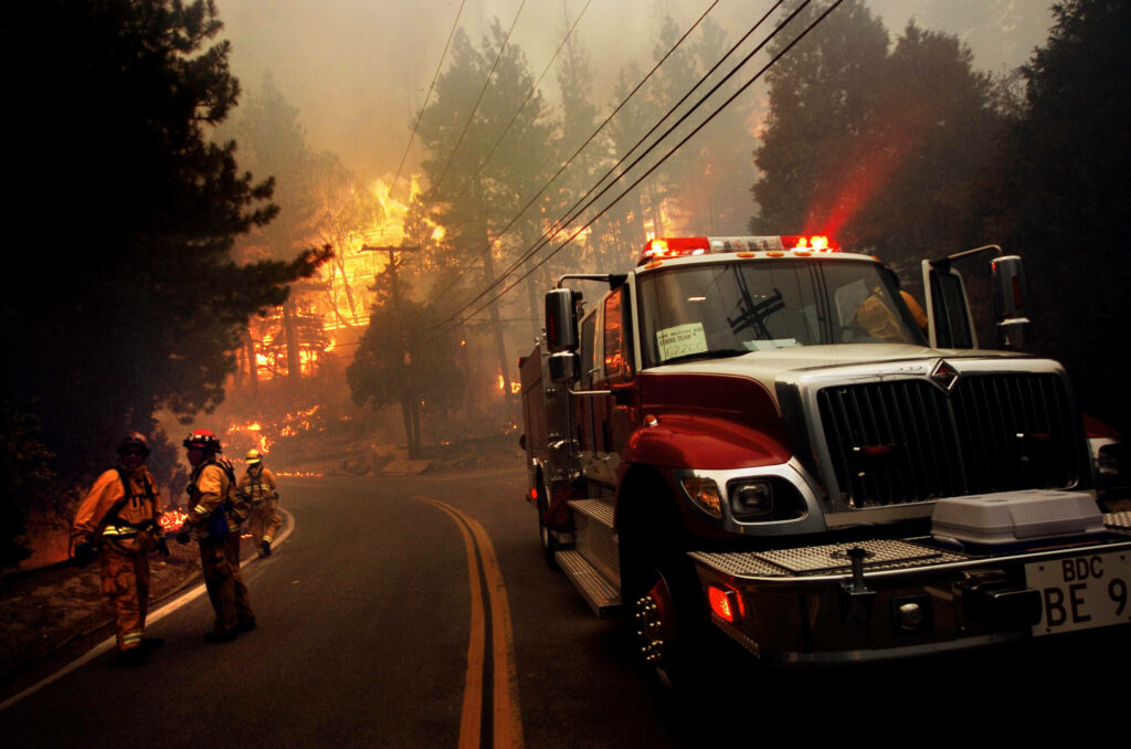 Fireman battles raging forest wildfire near firetruck showing courage and urgent action wallpaper