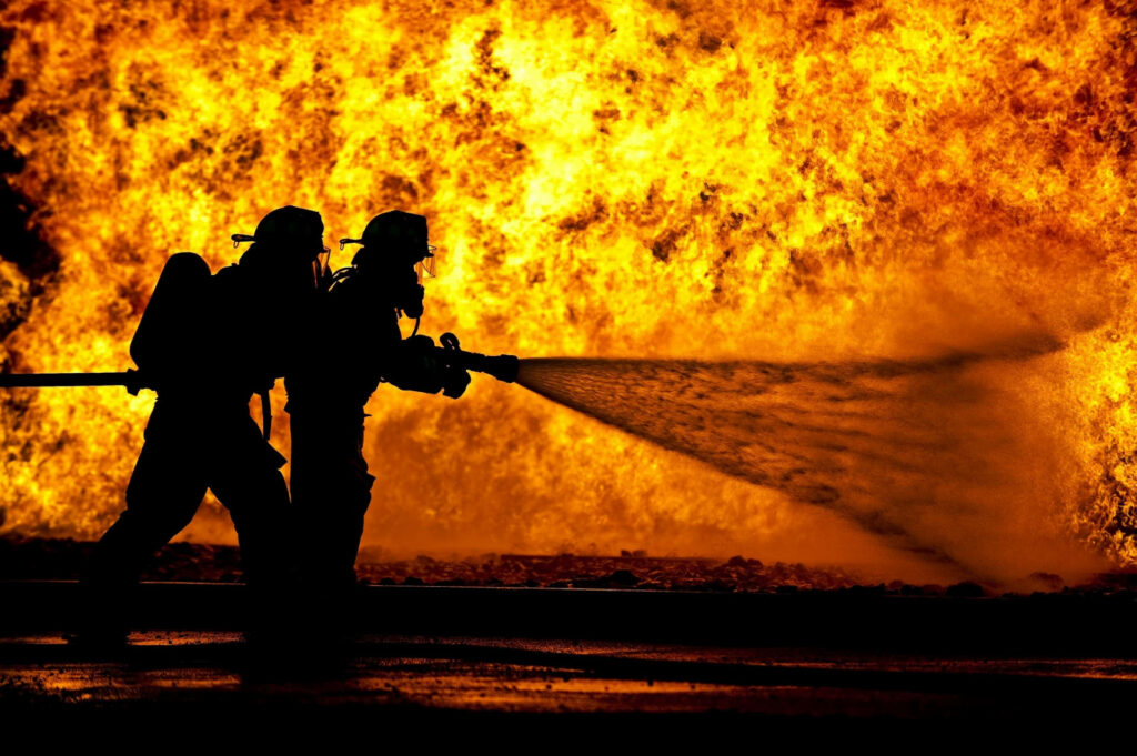 Silhouette of a brave fireman battling huge blazing flames intense fire wallpaper background