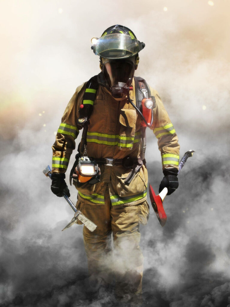 Fireman in full gear emerging from thick smoke carrying rescue tools symbolizing heroism Wallpaper