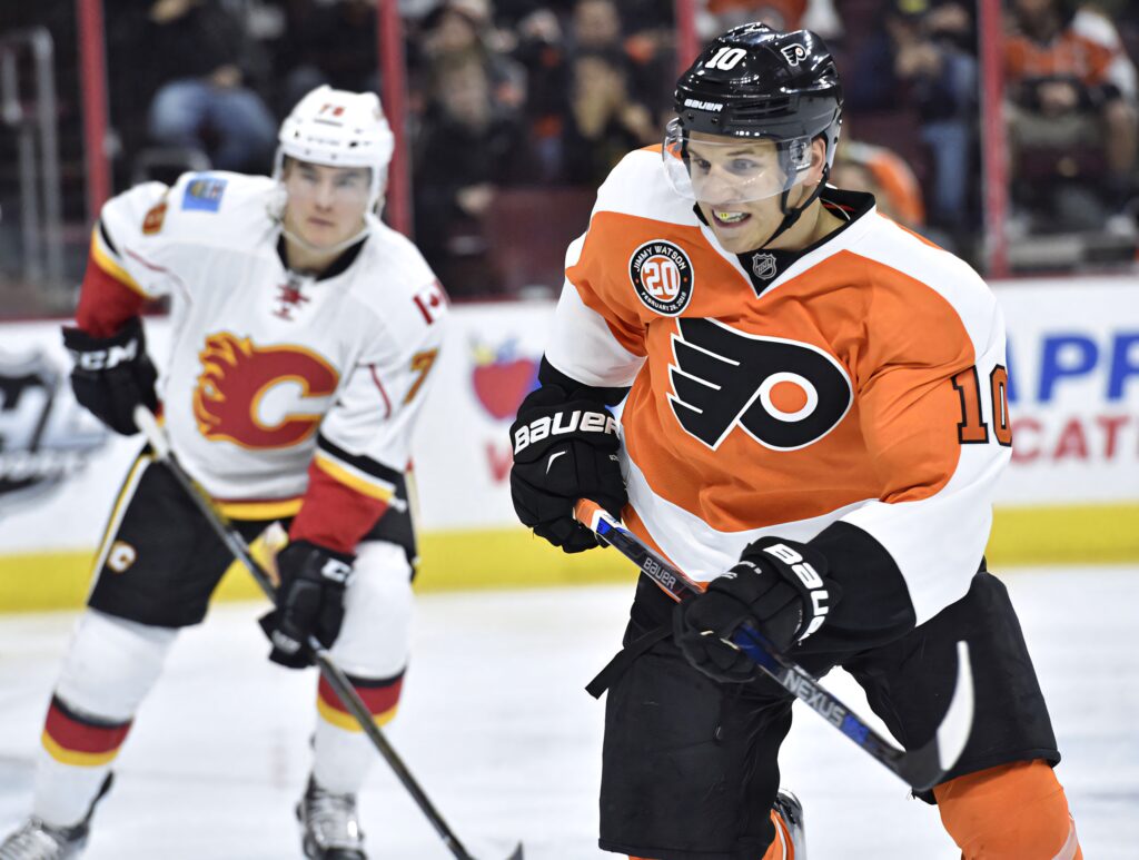 Flyers forward Brayden Schenn skates fast wearing orange and black against Calgary Flames red Wallpaper