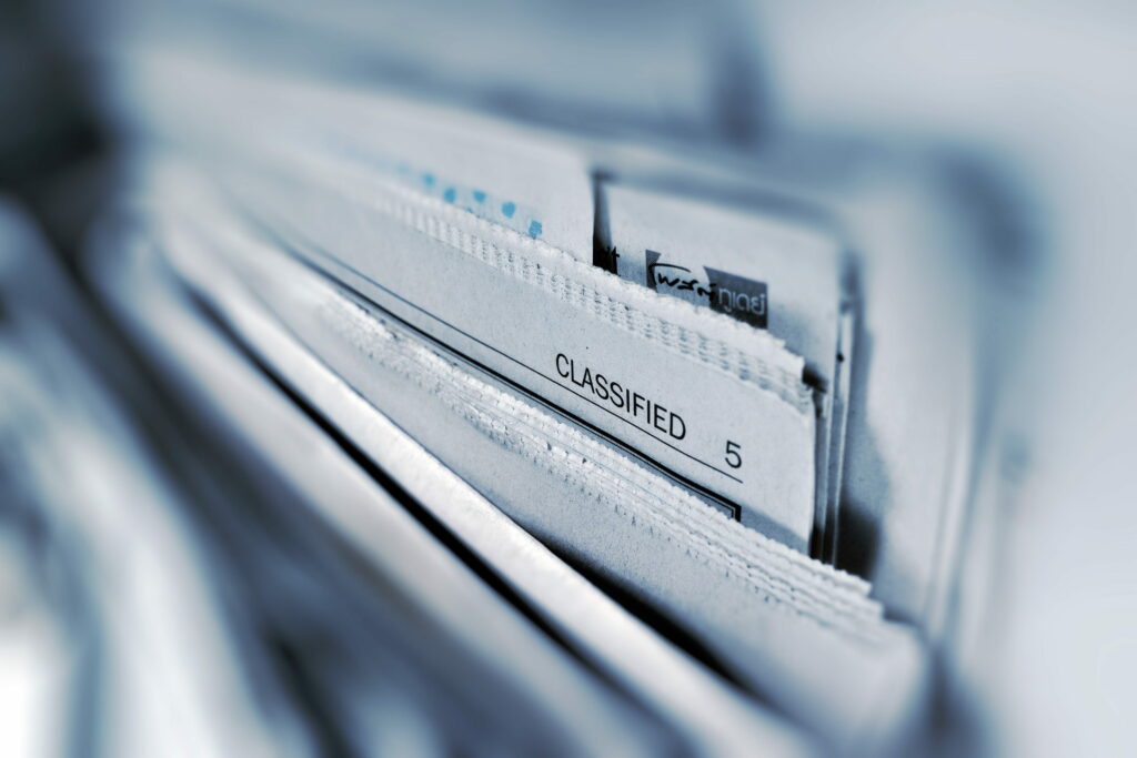 Macro shot of blue-toned Post Today newspaper stack focused on classified ads section background Wallpaper