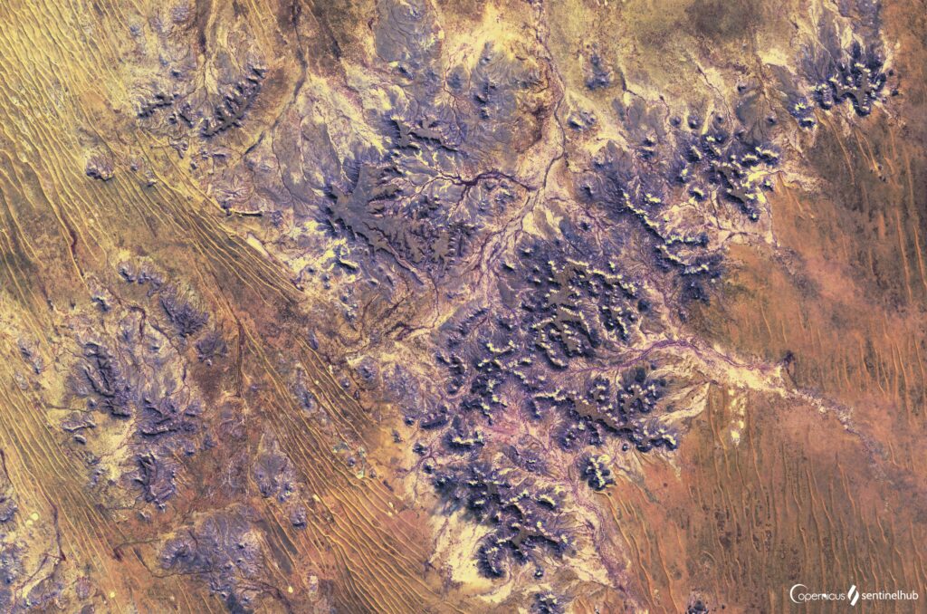 Aerial view of rugged textured landscape with earthy brown and purple tones artistic wallpaper background