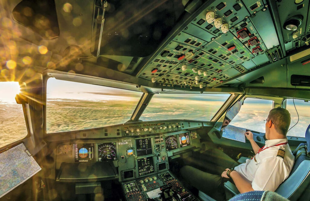 Sunset view from airplane cockpit with glowing clouds and detailed pilot controls wallpaper