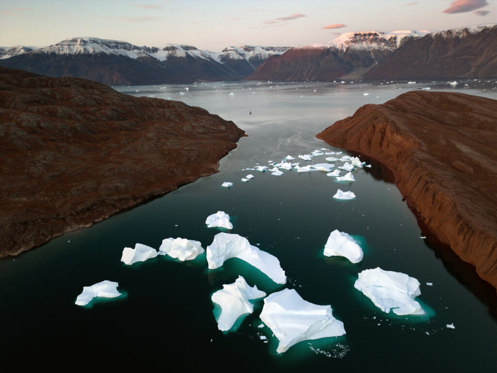 Arctic landscape with rugged mountains serene sea and icebergs under pastel sky wallpaper background