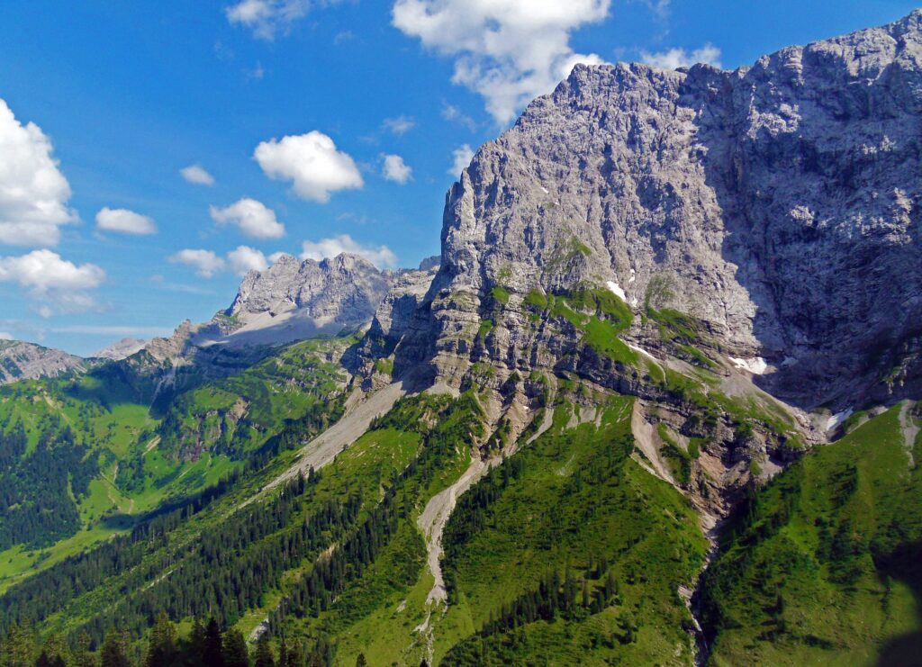Breathtaking Austrian Alps wallpaper with rugged mountains green valleys and bright blue sky background