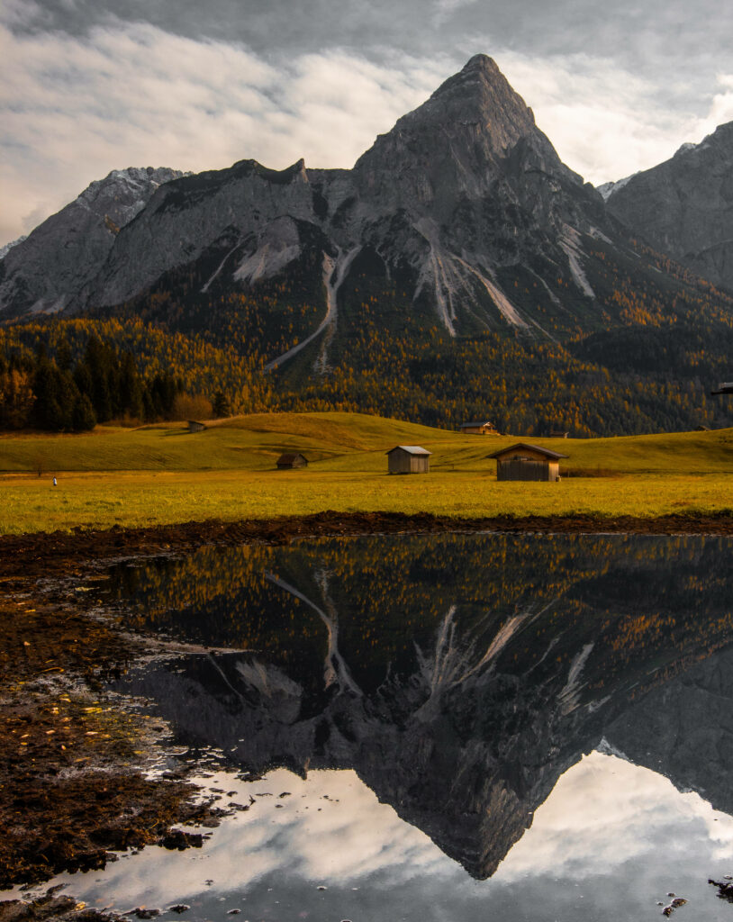 Vibrant green Austrian fields with rustic cabins mountains reflection scenic landscape wallpaper