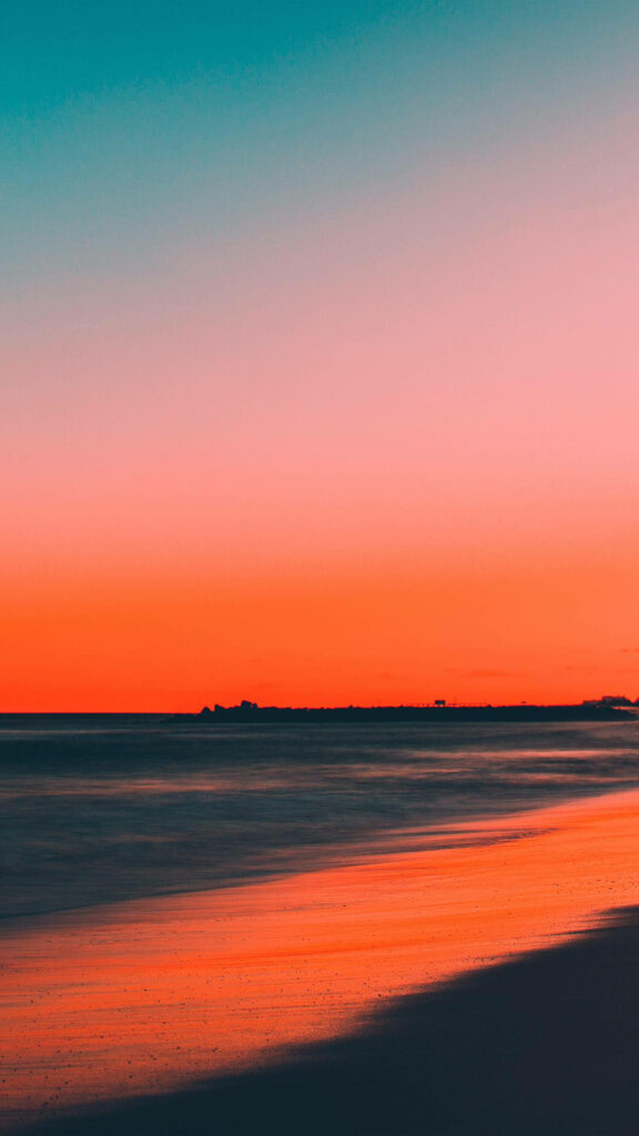 Stunning Beach Sunset: Vibrant Orange-Pink Sky Reflecting on Waves Wallpaper