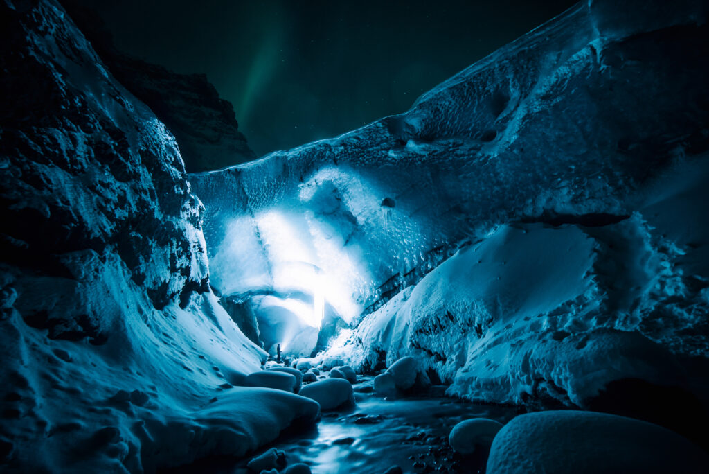 Stunning night ice cave wallpaper glowing blue with icy textures snow rocks under starry sky