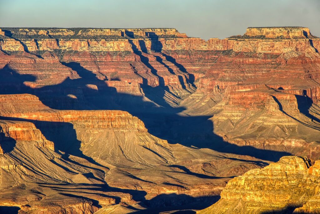 Breathtaking canyon landscape with warm earth tones and dramatic shadows on rugged rocks Wallpaper