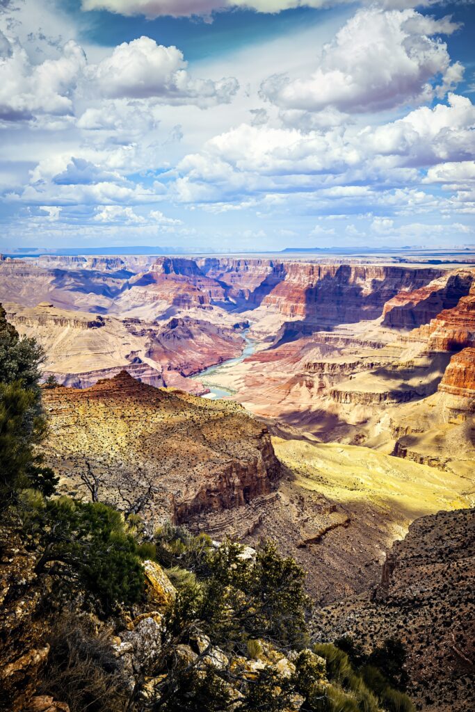 Breathtaking canyon landscape with red rocks green trees and dramatic clouds in bright sky background Wallpaper