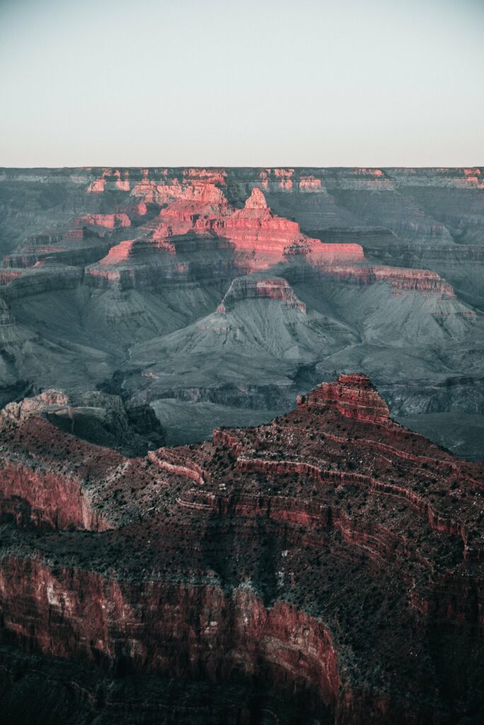 Dramatic canyon rock formations with layered slopes in soft natural light wallpaper background
