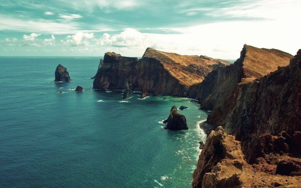 Breathtaking coastal landscape with rugged cliffs and deep blue sea under bright sky wallpaper