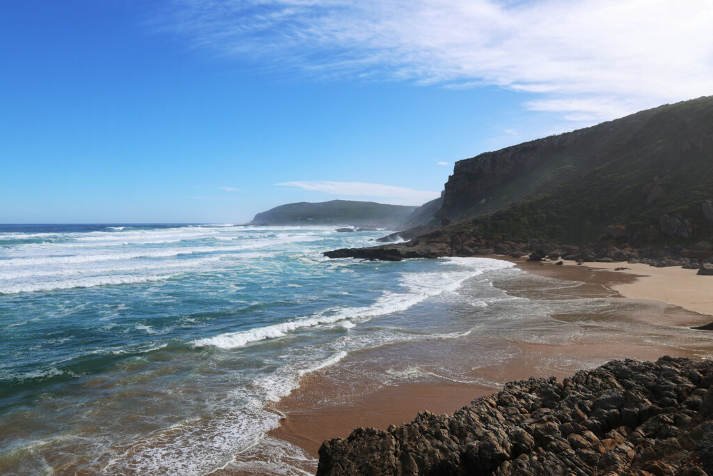 Breathtaking coastal landscape with rugged rocks golden sand turquoise waves and cliffs background Wallpaper