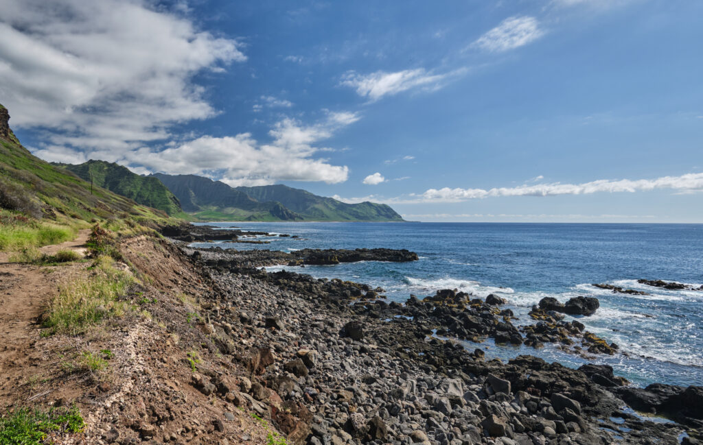 Breathtaking coastal landscape with rugged dark stones green hills and clear blue sea wallpaper