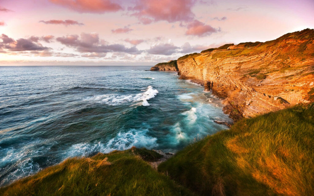 Breathtaking Coastal Sunset Wallpaper: Rugged Cliffs & Pink Clouds
