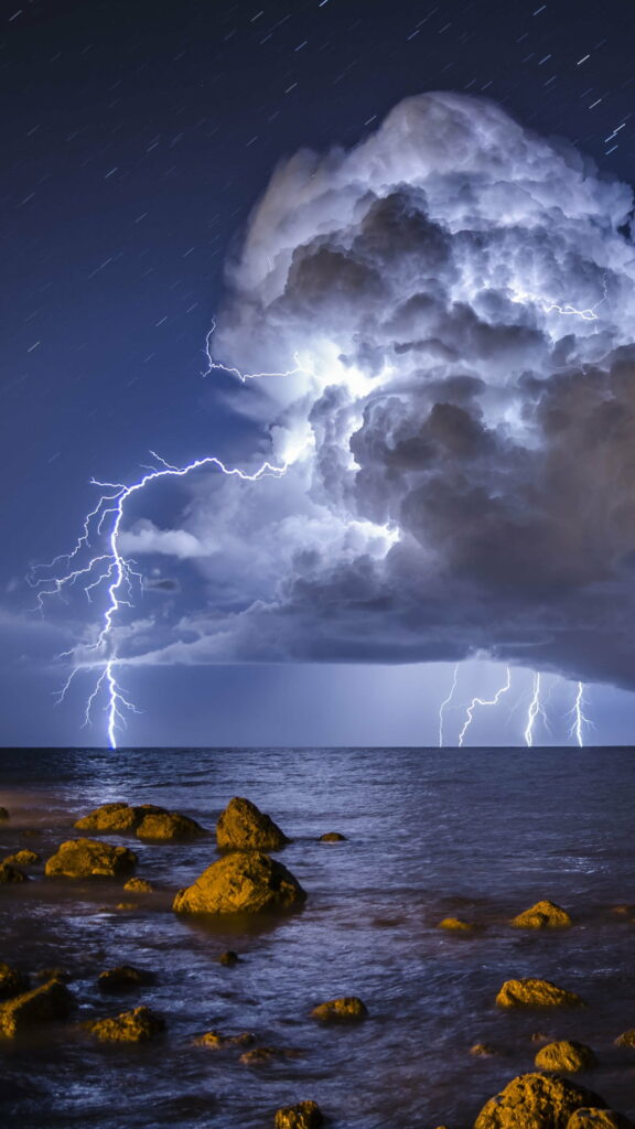 Dramatic Storm HD Phone Wallpaper: Lightning Over Rugged Shore