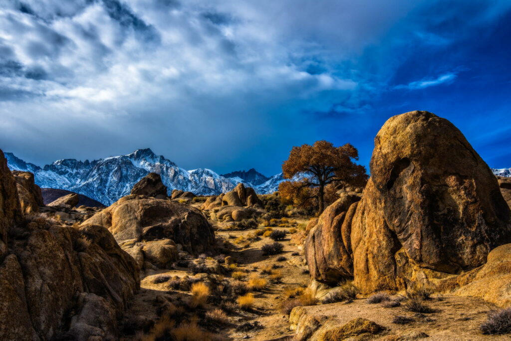 Dramatic desert landscape with rugged rocks snow-capped mountains vivid colors HDR wallpaper