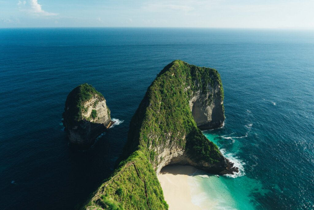Aerial view of rugged rock formation and turquoise waters by lush Indonesian island beach paradise Wallpaper