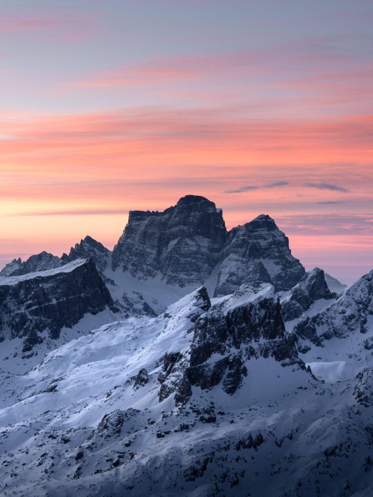 Snow-capped Italian Dolomites at sunset with rugged peaks and vibrant pastel sky wallpaper