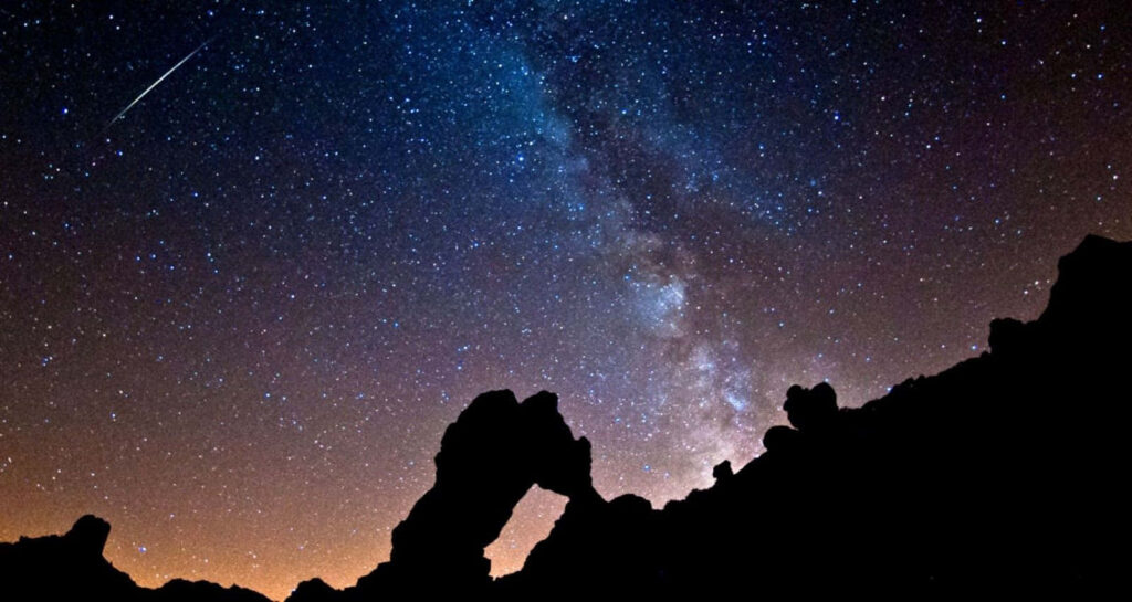 Enchanting Meteor Shower Wallpaper with Rock Arch and Starry Sky