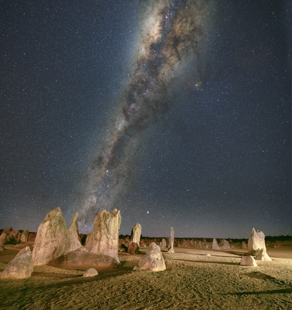 Jagged desert stones under a vibrant Milky Way starry sky breathtaking cosmic landscape background Wallpaper