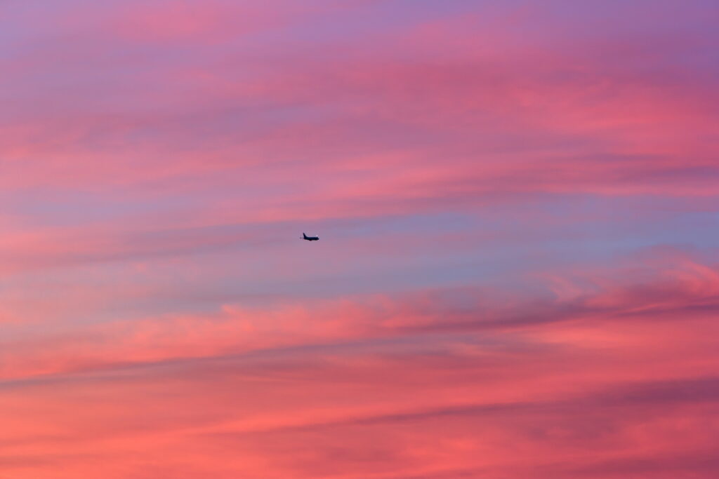 Tranquil Sky HD Wallpaper: Sunset Plane Over Colorful Clouds
