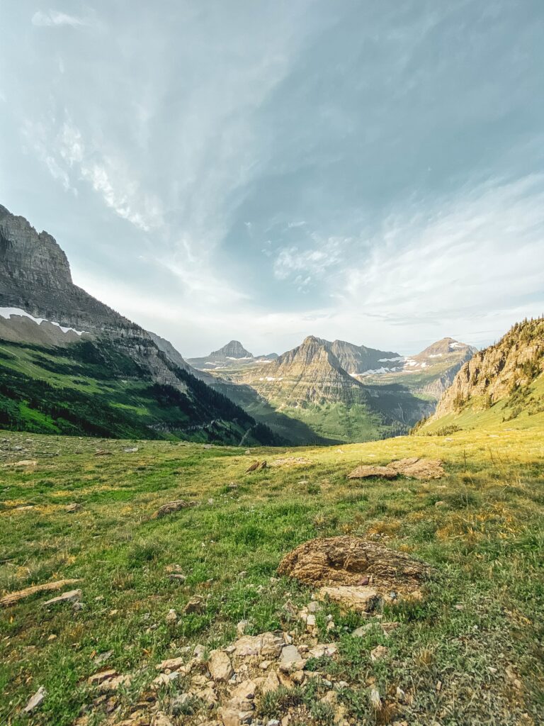 Breathtaking mountain landscape with rugged peaks lush green grass and a vast cloudy sky Wallpaper