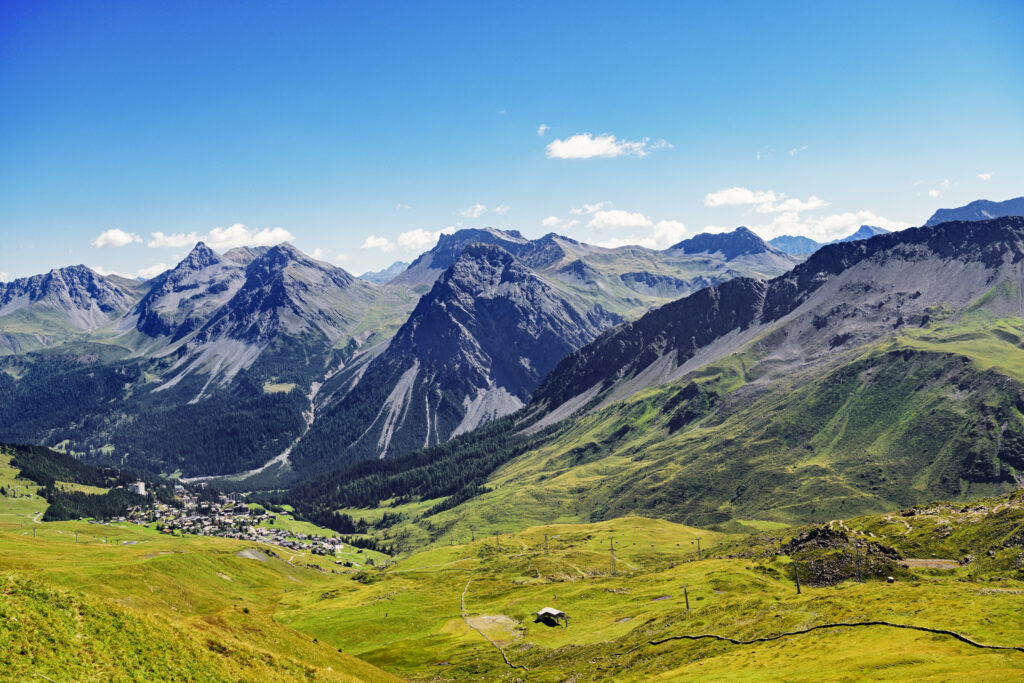 Breathtaking mountain landscape with rocky peaks and lush green valley under clear blue sky Wallpaper