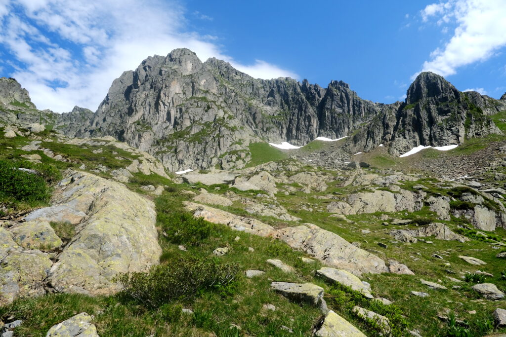 Breathtaking landscape with rugged rocks towering mountains vibrant blue sky grassy patches outdoors Wallpaper