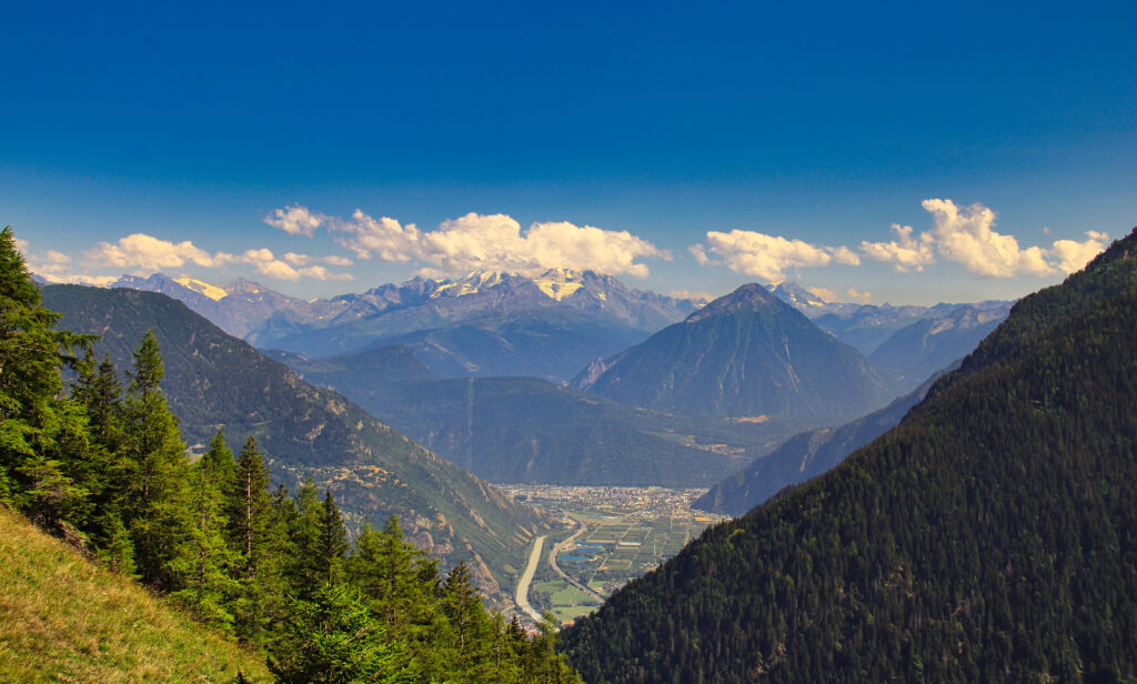Breathtaking mountain landscape with rugged rocks lush trees winding road and blue sky wallpaper