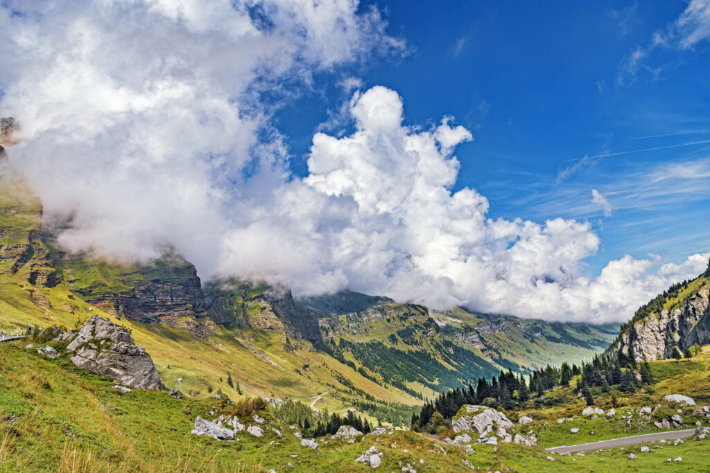 Breathtaking mountain landscape with rugged stones grassy slope dramatic clouds and vivid blue sky Wallpaper