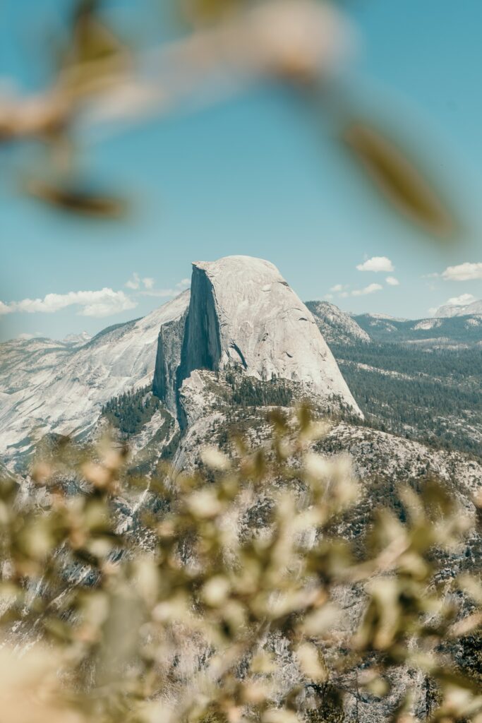 Sharp mountain peak over rugged forested range under clear blue sky daylight wallpaper background