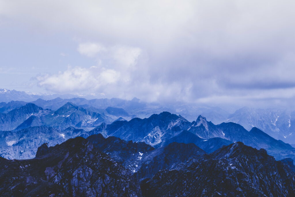 Breathtaking HD Mountain Wallpaper: Peaks & Clouds Against Blue Sky
