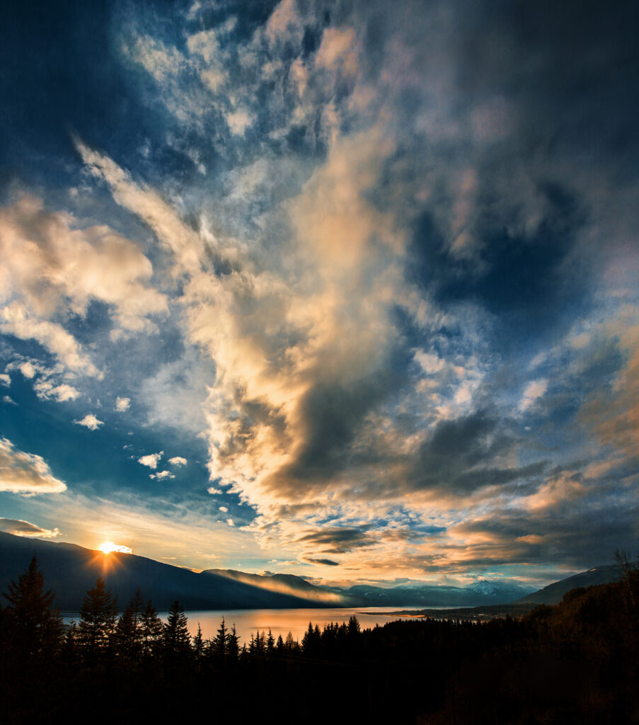 Sunset mountain landscape with vibrant clouds calm lake and tree silhouettes serene wallpaper background