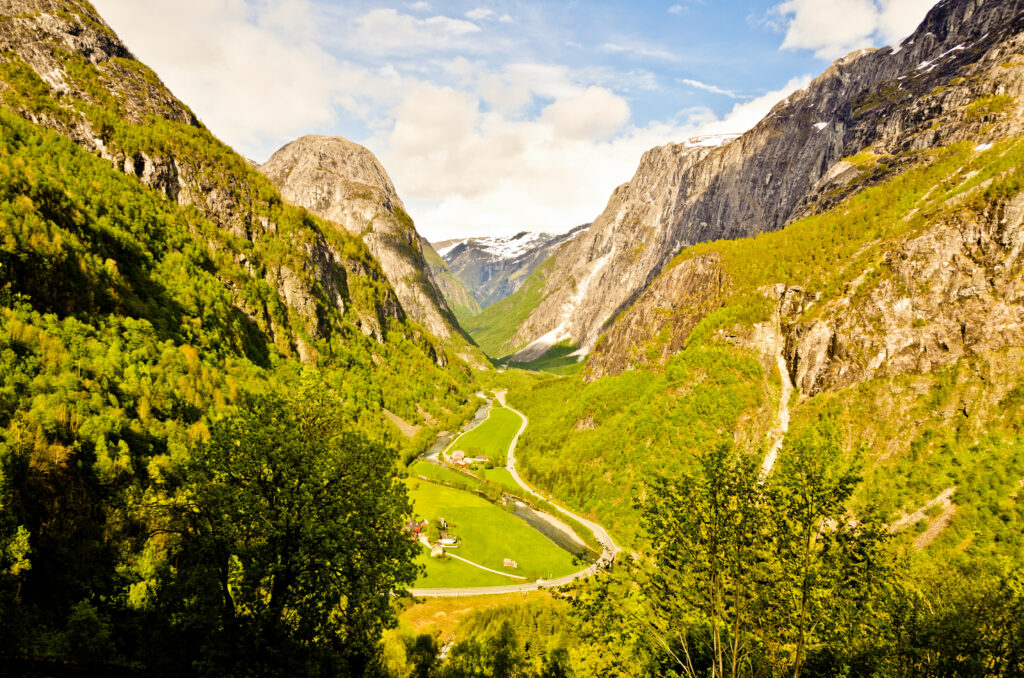 Breathtaking mountain valley with lush trees and winding trail under clear blue sky wallpaper